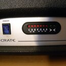Detail ovládacího panelu zesilovače značky CRATE. Panel obsahuje modrý vypínač s nápisem POWER, řadu červených LED diod nad označením tónů C D E F G…