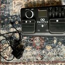 Černý looper s nápisem Sheeran LOOPER. Zařízení má dvě stoupací pedály, ovládací knoflík u nápisu FUNCTION - MENU a tři regulační potenciometry s pop…