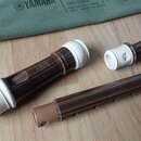 Na fotografii je rozložený dřevěný blokflét s bílými plastovými koncovými částmi. Na horní části nástroje je viditelné logo Yamaha a nápis YRS-312B.…