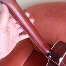 Fotografie zachycuje hnedkový krk akustické kytary z pohledu zezadu. Krk je vyroben z dřeva s viditelnou sletovanou strukturou a po stranách má světl…