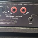 Detail zadní strany zesilovače s černým povrchem. Jsou zde vidět konektory s nápisy FOOT CONTROLLER, LOUDSPEAKER OUTPUTS 60 Watts RMS (s přepínačem S…