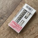 V průhledném plastovém obalu jsou umístěny kovové části mostu a strunovníku pro elektrickou kytaru v chromovaném provedení. Na červeném štítku je náp…