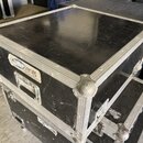 Černý transportní case s hliníkovými hranami a kovovými rohy. Na přední straně je nalepená bílá nálepka s modrým logem a nápisem servis, pod kterým j…