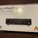 Krabice s audio rozhraním, na které je nápis U-PHORIA UMC204HD a text Audiophile 2x4, 24-Bit/192 kHz USB Audio/MIDI Interface with MIDAS Mic Preampli…