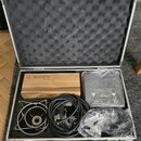 Otevřený hliníkový kufr s černé pěnovou výplní v víku. Uvnitř se nachází dřevěný box s nápisem se electronics SE GEMINI, šedý adaptér s označením MOD…