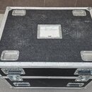 Černý transportní case s kovovými hranami a rohy. Na horní straně jsou čtyři kovové úchyty a uprostřed bílý štítek s nápisem ROBO. Povrch je viditeln…