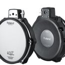 Dvě elektronické bubnové pady značky Roland. Levý pad má bílou membránu s nápisy „Roland“, „Head made by REMO“ a „V-Drums“. Pravý pad je z černého pl…