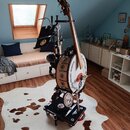 Sestava hudebních nástrojů na černém vozíku s kolečky. Obsahuje dřevěný kontrabas, bílý buben s nápisem „Lonty music section“ a černý notový stojan.…
