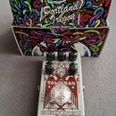 Šedý kytarový efekt v kovovém šasi s červeným grafickým panelem. Na panelu je nápis TALISMAN a v dolní části logo catalinbread s doplňkem MECHANISMS…