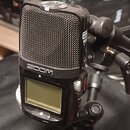 Černý digitální záznamový přístroj značky ZOOM s integrovanými mikrofony krytými kovovou mřížkou. Na horní straně je vidět přepínač s nápisem LO CUT…