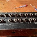 Zadávací panel černého mixážního pultu s řadou vstupních konektorů typu jack. V horní části je nápis INPUT a číslování kanálů od 1 do 12. Spodní řada…