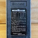 Zadní strana efektového pedálu značky BOSS. Uprostřed je umístěna tabulka s informacemi o napájecích adaptérech BOSS AC ADAPTOR pro různé napětí (100…