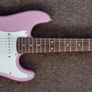 Růžová elektrická kytara s bílým pickguardem a hnědým hmatníkem. Na hlavě kytary je nápis Squier MINI by Fender. Nástroj vykazuje v dobrém stavu povr…