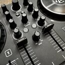 Černý DJ mixér s ovládacími prvky v podobě knoflíků a posuvníků. Na horní části je vidět nápis PARTY MIX a logo v podobě stylizovaného symbolu v kruh…