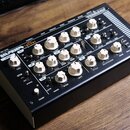 Černý efektový pedál v kovovém šasi s bílými otočnými knoflíky. Na horní straně je nápis „RETROsynth lancet“ a v pravém horním rohu značka „VERONA“.…