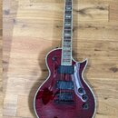 Elektrická kytara s červeným lakem a viditnou strukturou dřeva. Nástroj má dva humbuckery, tři ovládací knofíky a bílé lemování kolem těla. Na hrazen…