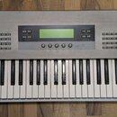 Stříbrný syntetizátor s klaviaturaí. V pravém horním rohu je nápis KORG Z1 MULTI-OSCILLATOR SYNTHESIZER. Horní panel obsahuje displej, množství tlačí…