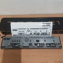 Kytarový efekt pedál stříbrné barvy s nápisy TECH 21 Fly RIG, EFX a SANSAMP. Na spodní straně jsou označení TAP/REVERB, DELAY, BLONDE/TUNER, BOOST a…