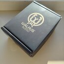 Černá papírová krabička s logem a nápisem WALRUS AUDIO ve zlaté barvě. Povrch krabice vykazuje mírné opotřebení v podobě drobných škrábanců a stínů.
