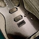 Elektrická kytara s tmavě šedým kovovými povrchem v tvrdém kufru. Nástroj má dva černé humbuckery, černý most a dvě ovládací knoflíky. Na těle ani na…