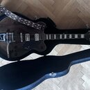 Tmavě hnědá polodublová elektrická kytara v černém tvrdém kufru. Na těle je viditelný nápis GRETSCH a na hradle nápis Bigsby. Kytara má dva snímače,…