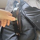 Detailní pohled na hranu černé kytary v otevřeném černém pouzdře. Lak na hraně těla je výrazně odloupaný a vykazuje značné opotřebení. Na fotce nejso…