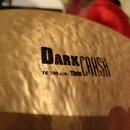 Detailní záběr na povrch mosazného činely s kovaným, nepravidelným povrchem. Na činely je černý nápis DARK CRASH a pod ním text 16"/40 cm Thin. Povrc…