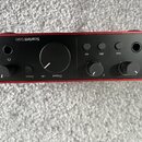 Červené audio rozhraní s černým horním panelem. Na šasi je nápis Scarlett Solo a dále označení Direct, Output, Air, 48V a Inst. Zařízení má tři otočn…