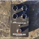 Černý kytarový pedál s nápisem Ampeg a označením SCRAMBLER Bass Overdrive. Má čtyři černé otočné knoflíky s bílými popisky Drive, Blend, Treble a Vol…
