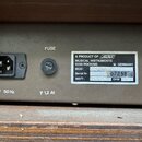 Detail zadní strany přístroje v hnědém provedení. Je zde vidět napájecí konektor, pojistka s nápisem FUSE a bílý štítek s textem: A PRODUCT OF Selton…