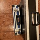 Na fotografii jsou dva transportní kufry s hliníkovými hranami a černými plastovými rohy. Menší modrý kufr má na ruketi nálepku s nápisem WISENT. Vět…