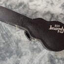 Černý tvrdý kufr na kytaru s texturovaným povrchem. Na spodní části je bílý nápis Gibson USA. Kufr vykazuje mírné opotřebení hran.