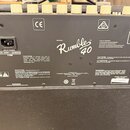 Zadní strana basového komba v černé barvě s texturou. Uprostřed je bílý nápis MODEL Rumble 40 TM a logo CE. V pravé části jsou vstupy AUX IN, PHONES,…