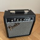 Kytarový kombo zesilovač s černým povrchem a stříbrnou síťovkou. Na ovládacím panelu jsou nápisy INPUT, GAIN, VOLUME, TREBLE, BASS a POWER, přepínač…