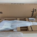 Otevřený hnědý karton s nápisem Squier BY FENDER a logem Company Brand. Uvnitř je v ochranné bílé tkanině zabalený korpus elektrické kytary s bílým p…
