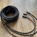 Černý audio kabel svalený do klubku. Kabel má na koncích zlaté konektory typu jack, které jsou u základny opatřeny zelenými a červenými označenými pr…