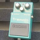 Tyrkysový kytarový efekt s nápisy Tremolo TR-2 a BOSS. Na horní části jsou tři bílé ovládací knoflíky s popisky RATE, DEPTH a nečitelným nápisem upro…