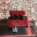 Červený efekt pedál s nápisem STANLEY CLARKE SIGNATURE WAH WAH by EBS Sweden AB a podpisem Stanley Clarke. Na horní straně jsou tři černé ovládací kn…