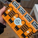 Čtyři oranžové papírové krabičky s černým potiskem, které obsahují elektronické lampy. Na každé krabičce je nápis Tube Amp Doctor™, SELECTED TUBES a…