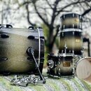 Sada bubnů s povrchem v černé a zlaté barvě s glitrovým efektem. Na malém bubnu je viditelné logo „Dwadel Master Series“. V popředí leží chromované p…