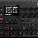 Černý digitální sekvencer a syntetizátor s nápisem Syntakt. Zařízení má displej, na kterém je vidět text 12 Track Drum Computer & Synthesizer a název…