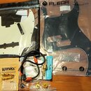 Sada příslušenství pro kytaru v plastových obalech. Obsahuje bílý a černý pickguard s nápisem FLEOR, kabel s červenými konektory, USB datový kabel v…