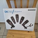 Bílá krabice s nápisem SAMSON a označením DK705 // 5-PIECE DRUM MIC KIT. Na obalu je zobrazeno pět černých mikrofonů, přičemž na nich jsou viditelné…