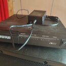 Černý stolní přijímač s nápisem SHURE a označením SC4 RECEIVER. Na předním panelu jsou nápisy DIVERSITY, R F LEVEL, AUDIO LEVEL a POWER. V pravé doln…