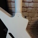 Záda bílé elektrické kytary s výrazným, hranatým tvarem těla. Povrch je hladký a lesklý, v horní části těla je vidět malý černý knoflík. V dolní část…