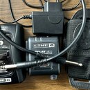 Sada bezdrátového systému Line 6 Relay G30 složená z odesílače, přijímače a napájecího adaptéru. Na zařízeních jsou viditelné nápisy LINE 6 a RELAY G…