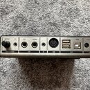 Zadávací panel elektronického hudebního zařízení s kovovým povrchem. Jsou zde viditelné nápisy VOLUME, HEADPHONES, LEFT, RIGHT, OUT, IN, MIDI, USB a…