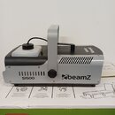Šedý kouřový stroj s černými plasty a úchytem. Na boku je uveden model SI1500 a logo beamZ. Zařízení vykazuje mírné opotřebení povrchu v horní části.
