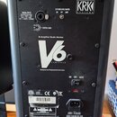Zadní strana černého studiového monitoru značky KRK SYSTEMS. Na zadním panelu je nápis Bi-Amplified Studio Monitor V6 SERIES 2 a text Designed and En…