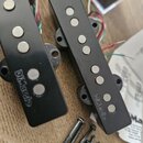 Dvě černé humbuckery s viditelnými polkovými magnety. Na obou je vyražen nápis DiMarzio. Vedle nástrojů jsou rozházené šrouby a barevné vodiče.